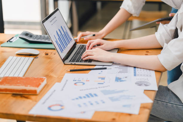 istock Two business colleagues working on financial analytics with graphs and charts on a laptop in a modern office. 2148804430