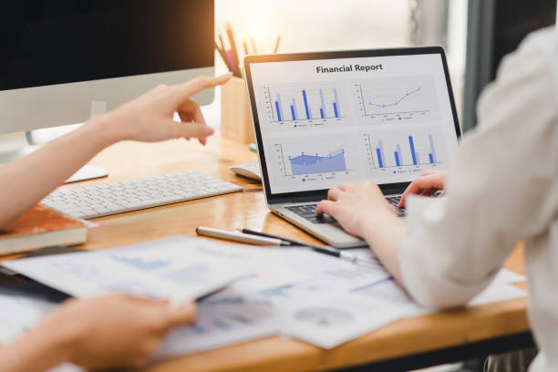 istock Two business colleagues working on financial analytics with graphs and charts on a laptop in a modern office. 2148804434
