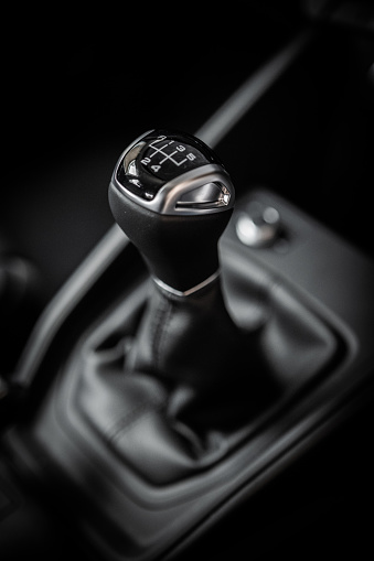 Gear stick with leather closeup from side view. Dark black and white manual car interior. Gear lever, gearshift, shifter, transmission lever.