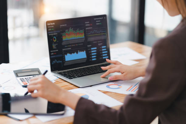 Businesswoman or an accountant team are analyzing data charts, graphs, and a dashboard on a laptop screen in order to prepare a statistical report and discuss financial data in an office.