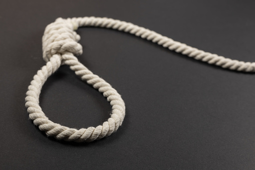 Rope noose for hangman made of natural fiber rope on a grainy gray wall. Hemp rope knot for gallows and Hang man.