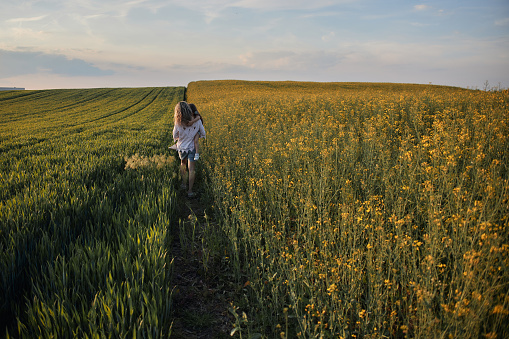 Young mother and daughter in field on a sunset. Single mother is carrying little girl.