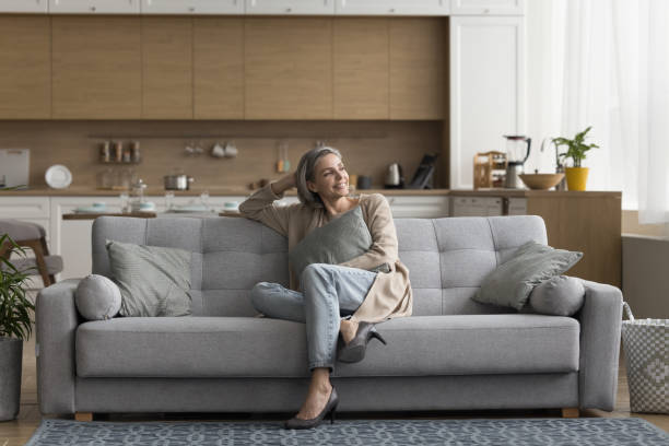 istock Happy dreamy female sitting on sofa relaxing looking out window 2148806671