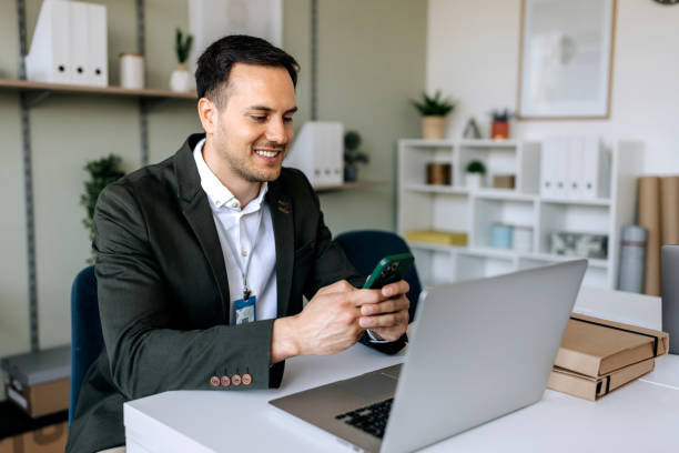 istock Well dressed businessman text messaging on smart phone while working at the office 2148807132