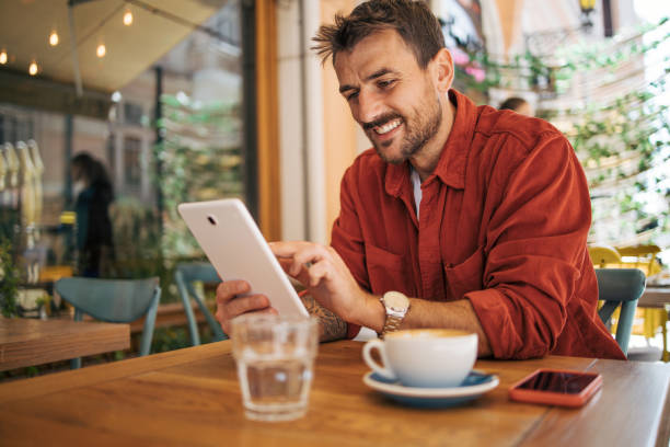 istock An adult man is sitting in a restaurant and using a digital tablet. 2148807431