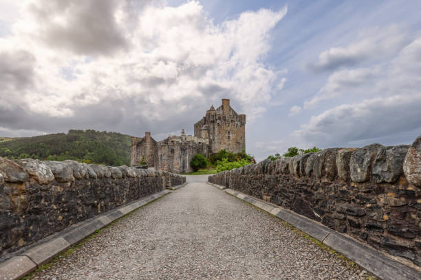 le château d’eilean donan se dresse sous un ciel spectaculaire, vu depuis l’approche du pont de pierre, incarnant des siècles d’histoire écossaise - scotland castle highlands region scottish culture photos et images de collection