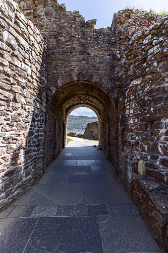 Drumnadrochit - United Kingdom. May 25, 2023: An ancient archway at Urquhart Castle provides a unique vantage point, blending the rugged textures of its stone walls with the tranquil beauty of Loch Ness in the distance