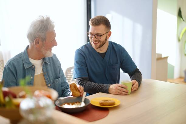 istock Smiling man talking with his caregiver at home 2148809264