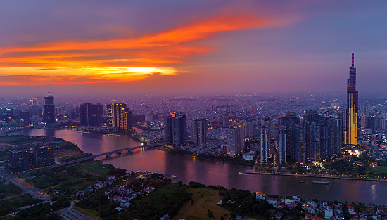 Ho Chi Minh city, Viet Nam, March 29, 2024: Aerial view of Asia city at sunset by drone with Landmark 81 skycraper modern building, boat on Saigon river, night skyline of Vietnam