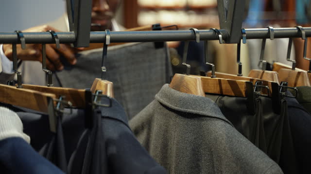 Black man choosing pants in luxury clothing store