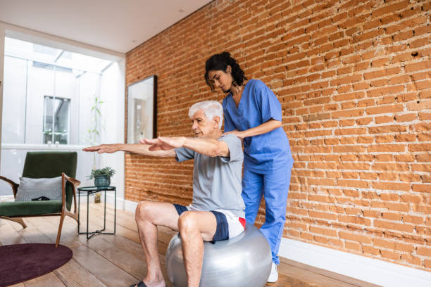 istock Physiotherapist helping senior man exercising at house 2148812298