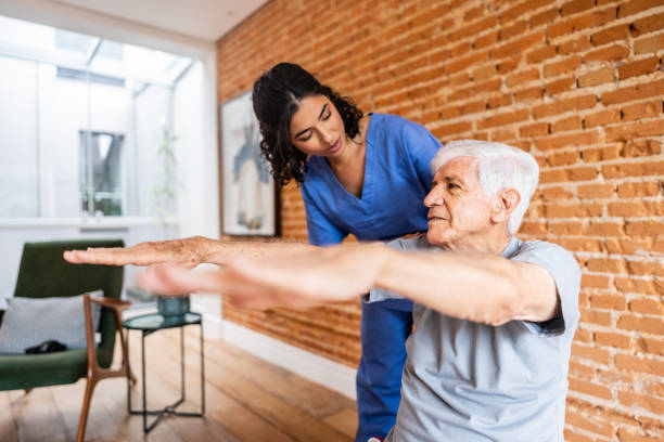 istock Physiotherapist helping senior man exercising at house 2148812329