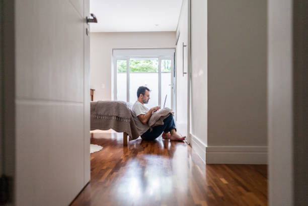 istock Mature man using computer sitting on the floor at home 2148812559