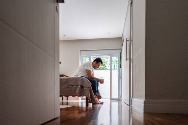 Worried mature man sitting on bed at home