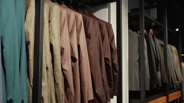 Strict premium expensive luxury suits hang in a row on hangers in large quantities. Business suit shop