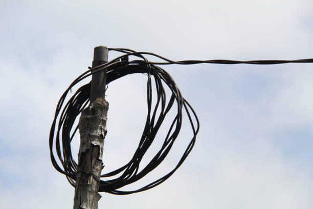 Electric cables with bamboo power poles on a blue sky background in a sunny morning. suitable for industrial themes and backgrounds
