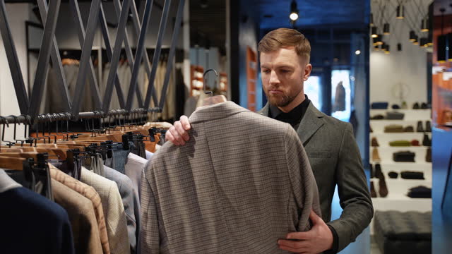 Handsome man walking in clothing store. A man buying new clothes in the shop