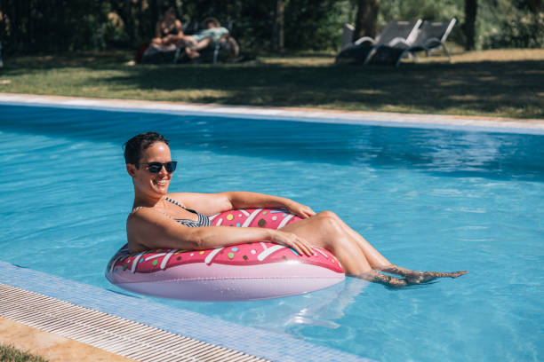 istock A woman is floating on a pink donuts float in a pool 2148813960