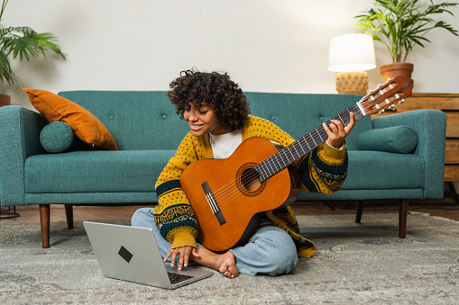 Blogger guitarist. Happy African American girl blogger playing guitar singing song recording vlog. Social media influencer woman streaming recording at home studio. Music content creator broadcast