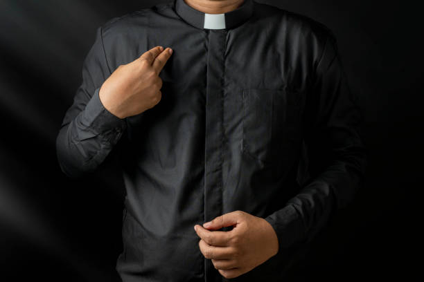 istock Young priest doing cross sign on his body isolated on black background. 2148814192