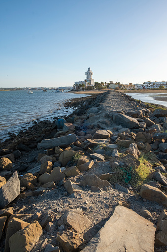 Isla Crisitna, Huelva, Spain - August 13, 2023: The lighthouse, at Isla Cristina and the beach Playa el Cantil, as seen from Punta del Moral, near Ayamonte, Huelva Province, Andalucia, Spain
