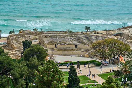 Tarragona, Spain - April 16, 2024: The ruins of the Tarraco Amphitheater stand proudly against the sea, a silent witness to Spains rich history, attracting visitors and tourists alike.