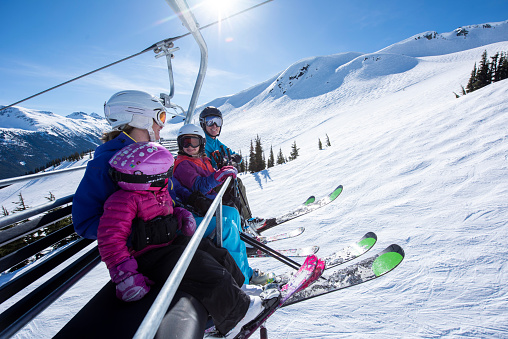 Ski family ride chairlift together at Canadian ski resort on a sunny winter day