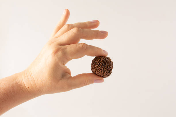 istock Hand holding Chocolate truffle balls Brigadeiro with chocolate flakes front view clean background 2148816080