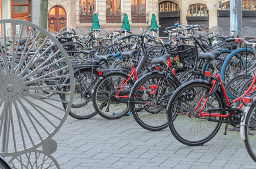 Bicycles of different colors and styles neatly parked in an equipped parking lot in Amsterdam.