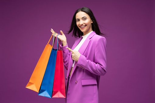 Portrait of her she nice well-dressed attractive lovely luxury pretty cheerful girl holding shopping bag isolated purple background