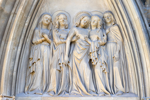 Group of five smiling female saints in long gowns with Mary Magdalene in the middle on gothic tympanum of main 14th century portal on street facade of the Minoritenkirche church in Vienna