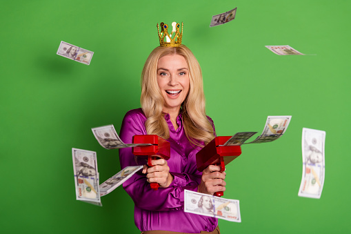 Photo of excited stunning lady golden crown shoot dollar bills money gun isolated on green color background.