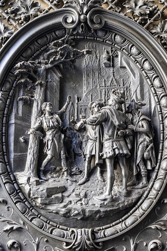 19th century door relief depicting the medieval nail-tree tradition where travelling journeymen would hammer nails into a tree for good luck and safe return. Bas-relief by Rudolf Weyr unveiled in 1891 on namesake town square in Vienna