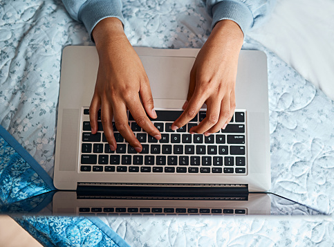 Top view, hands and laptop with typing on bed for social media search, email or research project with keyboard. Above, person or technology with blog writing, remote work and freelancer job in home
