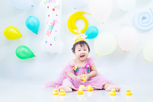 A young girl celebrates her 1st birthday. A young Asian girl celebrates her first birthday.
