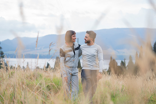 Latin couple from Bogotá Colombia of different ages, enjoy a walk through the meadow of the rural hotel using comfortable