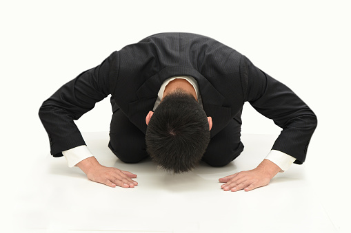 A businessman in a suit who kneels on the ground
