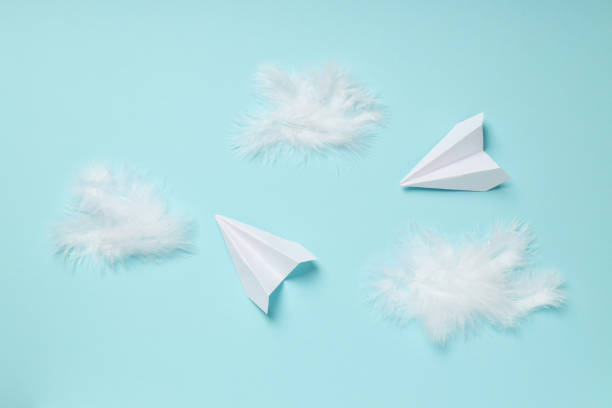 istock Paper planes and feathers on blue background 2148820454
