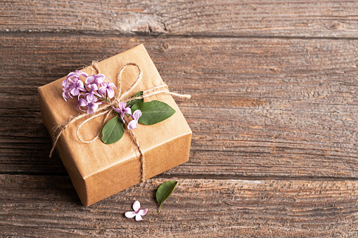 Gift box with lilac on wooden table