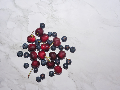 Ripe fresh cherries and blueberries on marble background