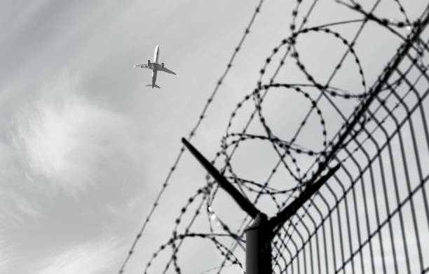 istock Barbed wire fence. Flying airplane in the background. 2148822307