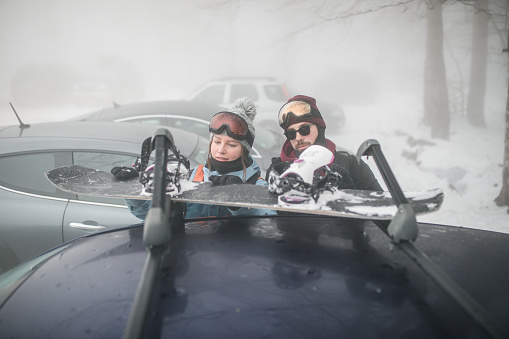 KAZKOVA POLYANA, UKRAINE - January 26, 2019: woman gathering to ski. car with opened trunk. parking