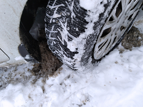 Dirty messy snow near car wheel. Mud, salt and chemicals on winter road. Ecology problem in city. Protection and wash auto concept. Environment conversation. Driving. Vehicle hubcap. Tire pressure.