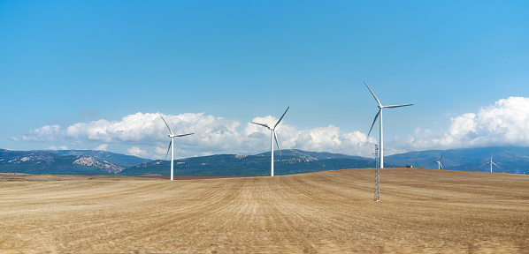 Wind farm in the foothills of Tarifa, Andalusia, Spain with turbines in agricultural fields against a mountain backdrop in a sustainable energy concept