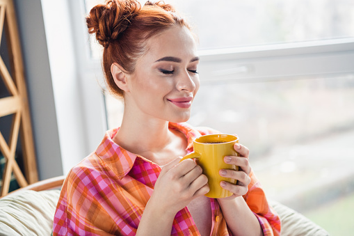 Photo of pretty lovely lady closed eyes hands hold coffee mug enjoy aromat free time chill apartment inside.