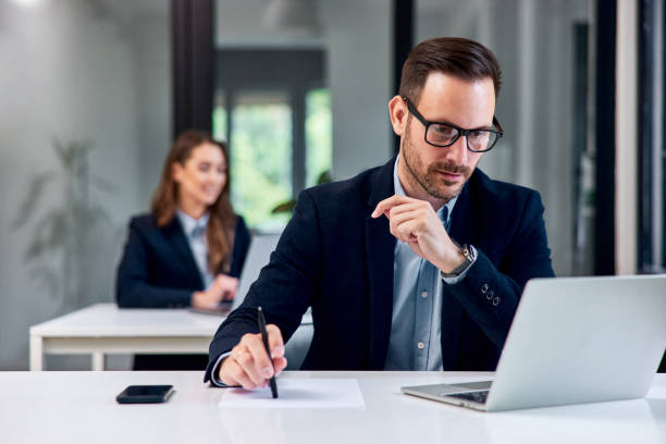 istock A hardworking businessman working over a laptop and writing notes on paper. 2148823011