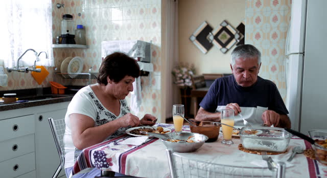 Aged pair enjoying a simple midday meal, a unique glimpse into the daily life of an older married couple in their quaint South American abode