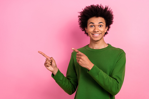 Photo of happy positive guy demonstrate empty space adverts isolated pastel color background.