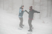 Loving couple snowboarding down the slope holding hands on a foggy winter day and enjoying the adventure