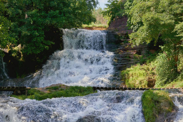 istock Cascade waterfall in rocks overgrown with trees and greenery 2148825103